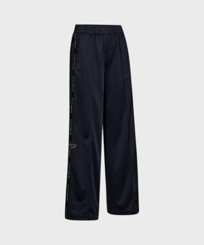 Navy trackpants fra Haute L’Amitié med afslappet pasform og logo tape langs benene – sporty og moderne bukser i 100% polyester.