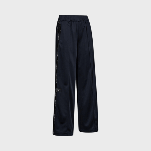 Navy trackpants fra Haute L’Amitié med afslappet pasform og logo tape langs benene – sporty og moderne bukser i 100% polyester.