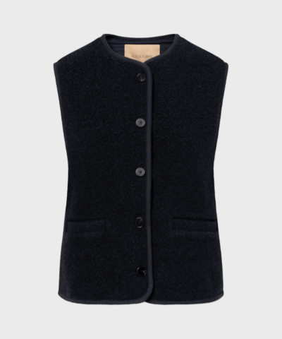 Mørk navy uldvest med rund hals og knapper – CAS TEDDY fra Rue de Tokyo, bæres over grå strik af model på 175 cm.
