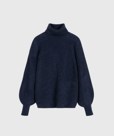 Magoo sweateren fra By Malene Birger er en luksuriøs rullekrave i mohair og uld, designet til kolde dage med stil. Den løse pasform og klokkeærmer skaber et moderne og feminint udtryk, mens de ansvarlige materialer sikrer bæredygtighed. Perfekt til lag-på-lag styling – shop den hos Merci Give.