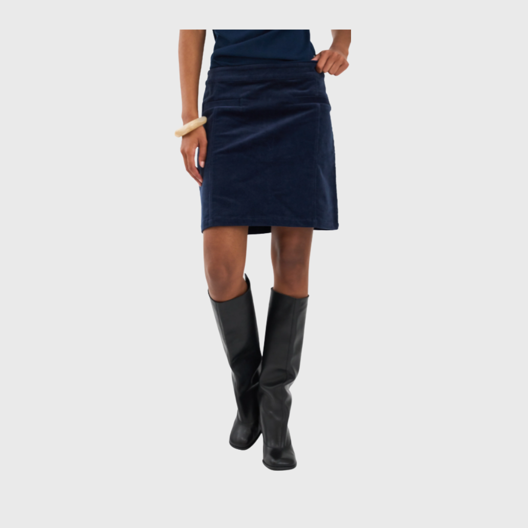 Ivy Copenhagen Sign Cord Mini Skirt i farven Deep Navy Blue er en moderne og feminin fløjlsnederdel med høj talje og A-formet snit. Den bløde fløjl og de diskrete detaljer giver et stilrent look, der passer perfekt til både hverdag og fest. Style den med en løs skjorte eller blazer for et cool, urbant udtryk. Køb hos Merci Give og få mode med kant og komfort.