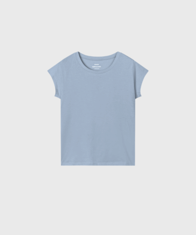 En klassisk T-shirt fra Mads Nørgaard, fremstillet i blød og let bomuld. Teasy Tee har en tætsiddende pasform og korte, vifteformede ærmer, som giver et feminint og moderne udtryk. – perfekt til både hverdag og lag-på-lag styling.