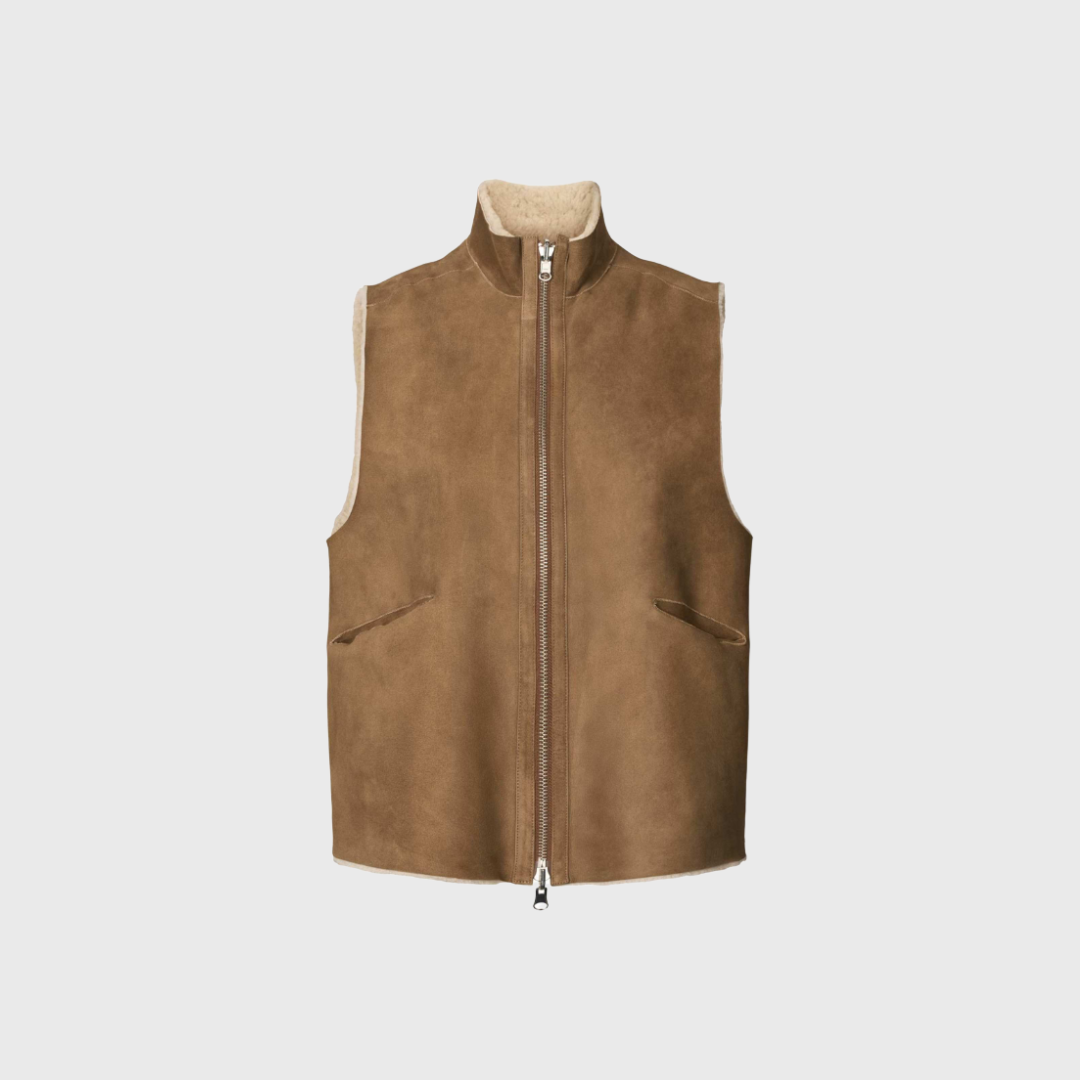 Rabens Saloner Shearling Vest Channe er den ultimative luksus til din vintergarderobe. Vesten er fremstillet i 100 % lammeskind med blød shearling, der giver varme og et eksklusivt look. Den mørkebrune og naturlige farvekombination gør den nem at style over strik, skjorter eller kjoler. Perfekt til lag-på-lag styling og et sofistikeret udtryk. Køb online med hurtig levering.