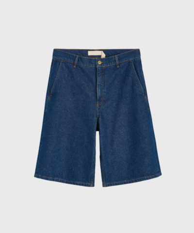 Opdag Carlo Denim Shorts – Mid Blue, klassiske lange denimshorts i 100% GOTS-certificeret økologisk bomuld. Med oversized pasform, mellemhøj talje og fine detaljer som håndsyede stikninger og Aiayu-logo patch. Perfekt til sommerens afslappede outfits med et stilfuldt touch.