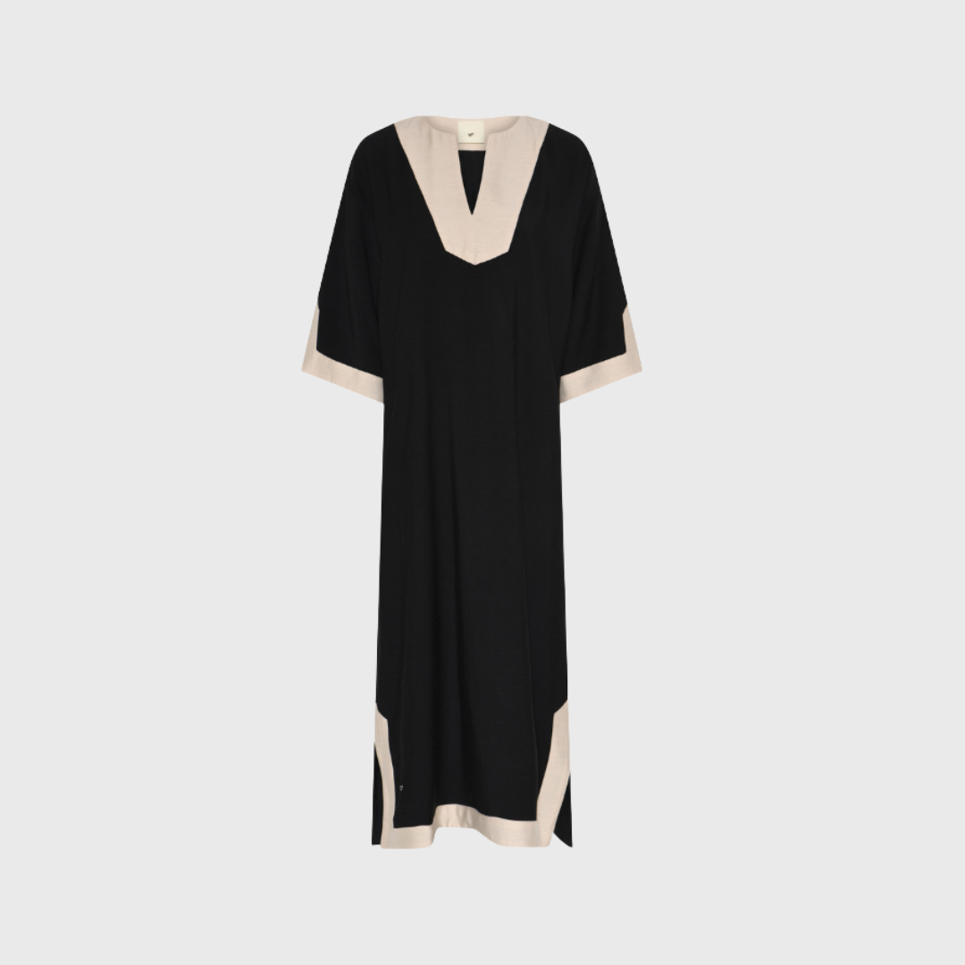 Opdag HMVigdis Dress – Black, en lang kjole med kontrastkant og dyb V-hals. Fremstillet i en luksuriøs blanding af viskose, polyester og hør, der sikrer komfort og et flot fald. Perfekt til både sommerdage og festlige anledninger. Et grafisk statement med moderne detaljer.