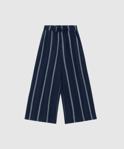 Opdag Storie Pants Stripe fra Moshi Moshi Mind – et par bløde og klassiske culottebukser i certificeret økologisk bomuld. De brede ben, elastiske talje og dekorative striber skaber et moderne og komfortabelt udtryk. Farven Dark Navy / White gør dem lette at style til både hverdagsbrug, arbejde og rejser. En tidløs og ansvarlig basisstyle i garderoben.