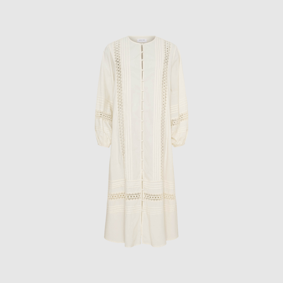 Lily LS Shirt Dress i White Sand er en feminin maxikjole i 100% bomuld med stofbetrukne knapper, hæklede detaljer og ballonærmer. Let, elegant og perfekt til forår og sommer.
