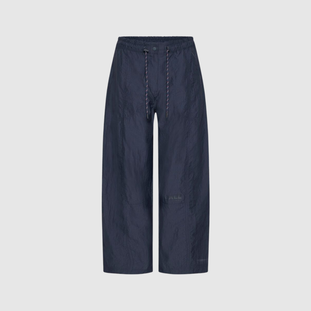 Opdag Bastella Curve Pant fra BALL – moderne bukser i vævet polyamid med curved fit, high waist og cropped længde. De kurvede ben giver et cool og trendy streetwear‑look, som er perfekt til både hverdag og sporty outfits. Farven Navy gør bukserne nemme at matche og ideelle sammen med resten af Bastella‑kollektionen.