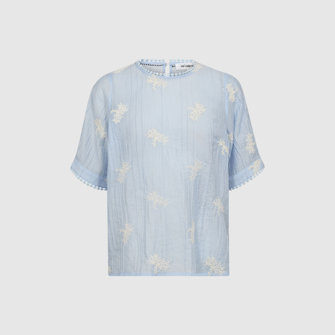 AmeliaCC Emb SS Blouse i Pale Blue er en let og feminin bluse med broderi og korte ærmer. Fremstillet i tencel og polyamid for et glat og behageligt fald. Perfekt til sommerlige outfits.