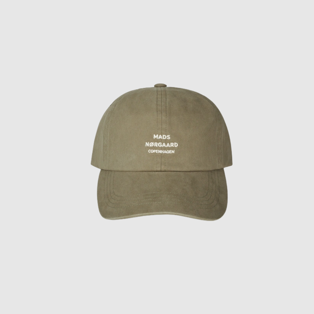 Mads Nørgaard Soft Twill Cash Cap Overland Trek er en minimalistisk og stilren kasket i 100% bomuld. Den army‑grønne farve giver et cool, moderne look, mens det broderede logo foran skaber et enkelt og ikonisk udtryk. Kasketten har buet skygge og justerbar rem, hvilket gør den både praktisk og komfortabel. Perfekt til både casual outfits og sporty hverdagslooks.
