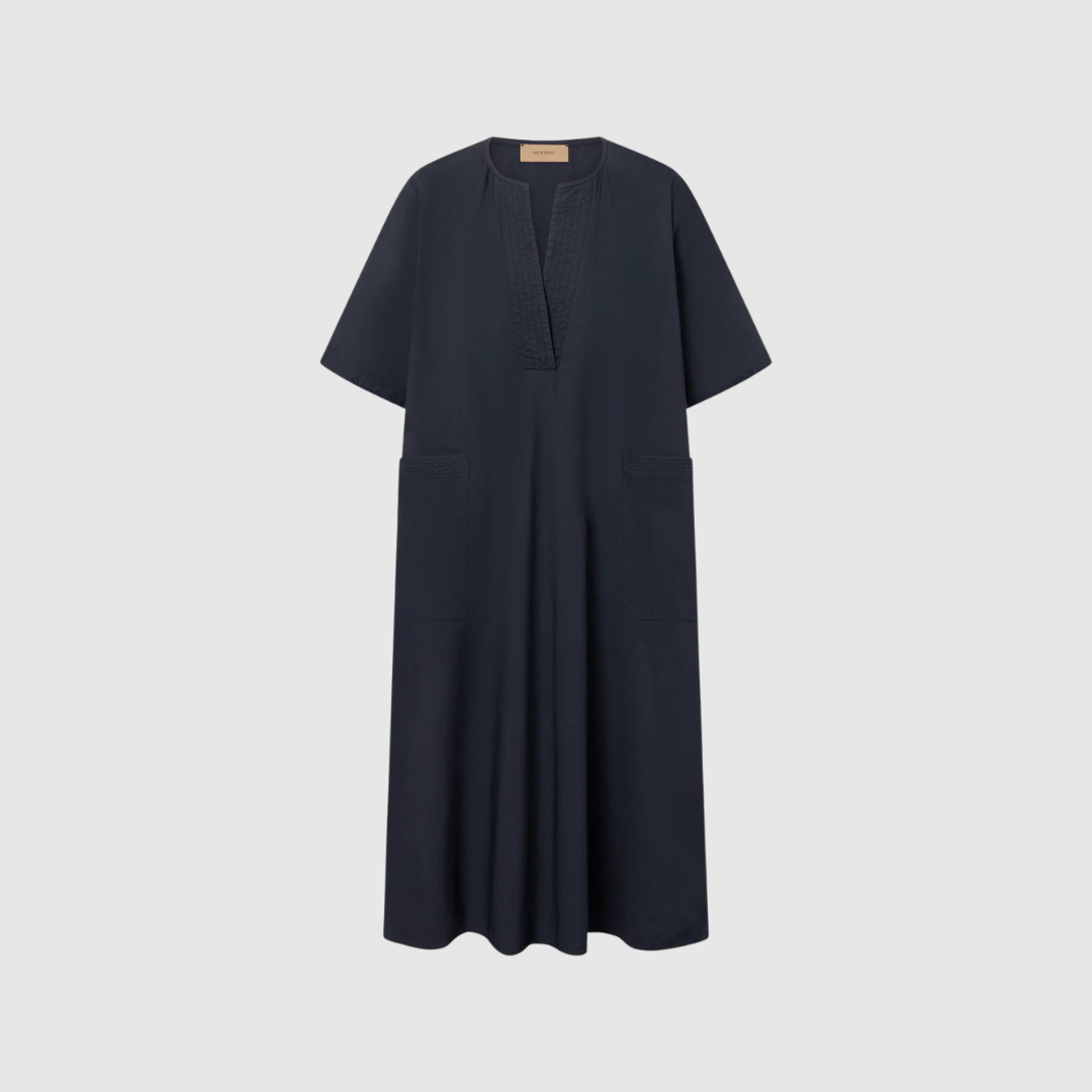 Rue de Tokyo Desi GMTD Poplin Dress Dark Navy er en elegant og afslappet kjole i 100% økologisk bomuld. Med A‑line snit, korte ærmer, V‑udskæring og praktiske lommer er den både stilren og funktionel. Perfekt til sommer, hverdagslooks og casual events.