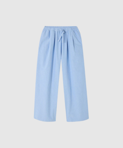 American Vintage Feoly Trousers i lyseblå Azurin er et par ballonbukser i 100% bomuld med elastisk talje, meleret struktur og et afslappet, feminint retro-look. Perfekt til både hverdag og afslappede outfits. Find dem hos Merci Give.