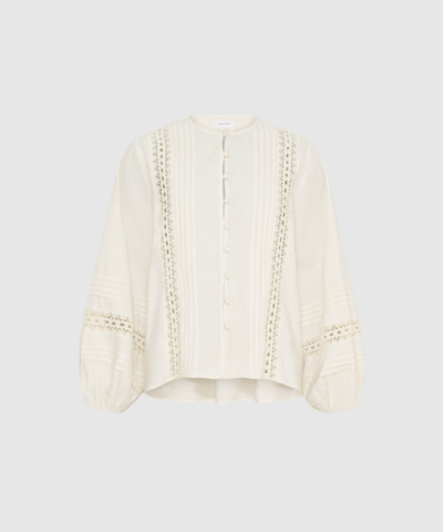 Lily LS Shirt i White Sand er en feminin skjorte i 100% bomuld med ballonærmer, stofbetrukne knapper, pleats og crochet‑detaljer. Elegant, let og perfekt til både hverdag og pæne anledninger.