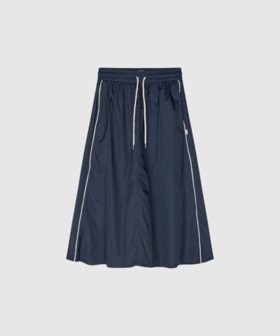 Caro Skirt fra Mads Nørgaard i Sky Captain er en let og sporty nederdel i 100% ripstop nylon med A‑snit og justerbar snøre i taljen. En moderne og funktionel style, der kan bruges både til hverdag og som del af et cool sæt med den matchende overgangsjakke. Find den hos Merci Give.