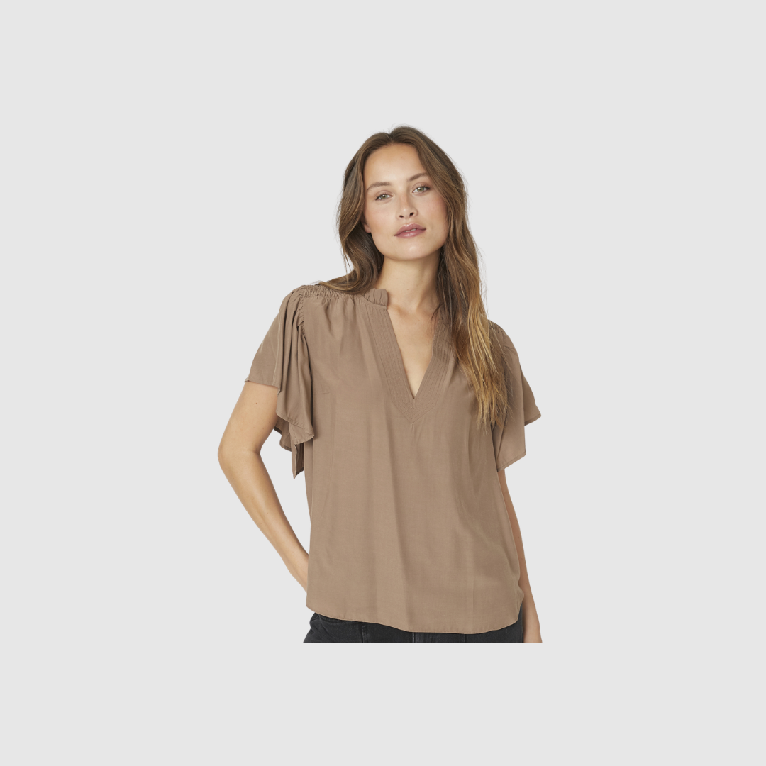 ToraCC Frill V‑top er en feminin top med flæsedetaljer og V‑udskæring. Fremstillet i let viskoseblanding i en smuk walnut‑farve. Perfekt til både hverdag og pænere anledninger. Find ToraCC toppen hos Merci Give.