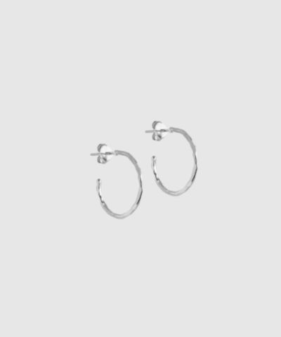 Organic Arena Small Hoops fra ENAMEL Copenhagen er små, elegante hoops i sterlingsølv med organisk, hamret overflade. Et tidløst og diskret smykke, perfekt til hverdagsbrug og minimalistisk styling. Find Organic Arena Hoops hos Merci Give.