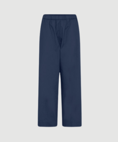 Melbourne Ankel Pant fra FRAU i farven Navy Blazer er en klassisk ankelbuks i 100 % økologisk bomuld. Bukserne har smal elastik i taljen, usynlige sidelommer og et lige benforløb, som giver et tidløst og komfortabelt look til både hverdag og arbejde. Find FRAU Melbourne Ankel Pant hos Merci Give.