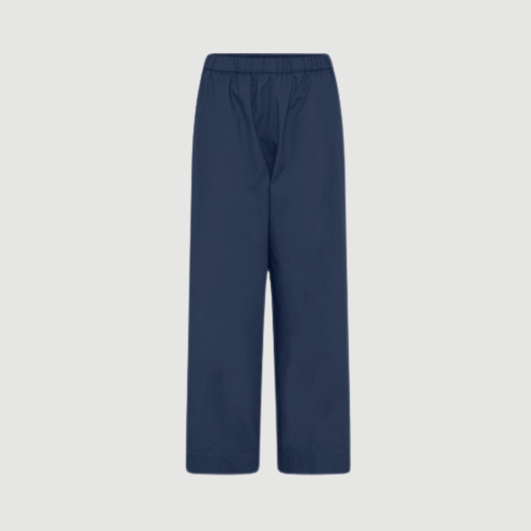 Melbourne Ankel Pant fra FRAU i farven Navy Blazer er en klassisk ankelbuks i 100 % økologisk bomuld. Bukserne har smal elastik i taljen, usynlige sidelommer og et lige benforløb, som giver et tidløst og komfortabelt look til både hverdag og arbejde. Find FRAU Melbourne Ankel Pant hos Merci Give.