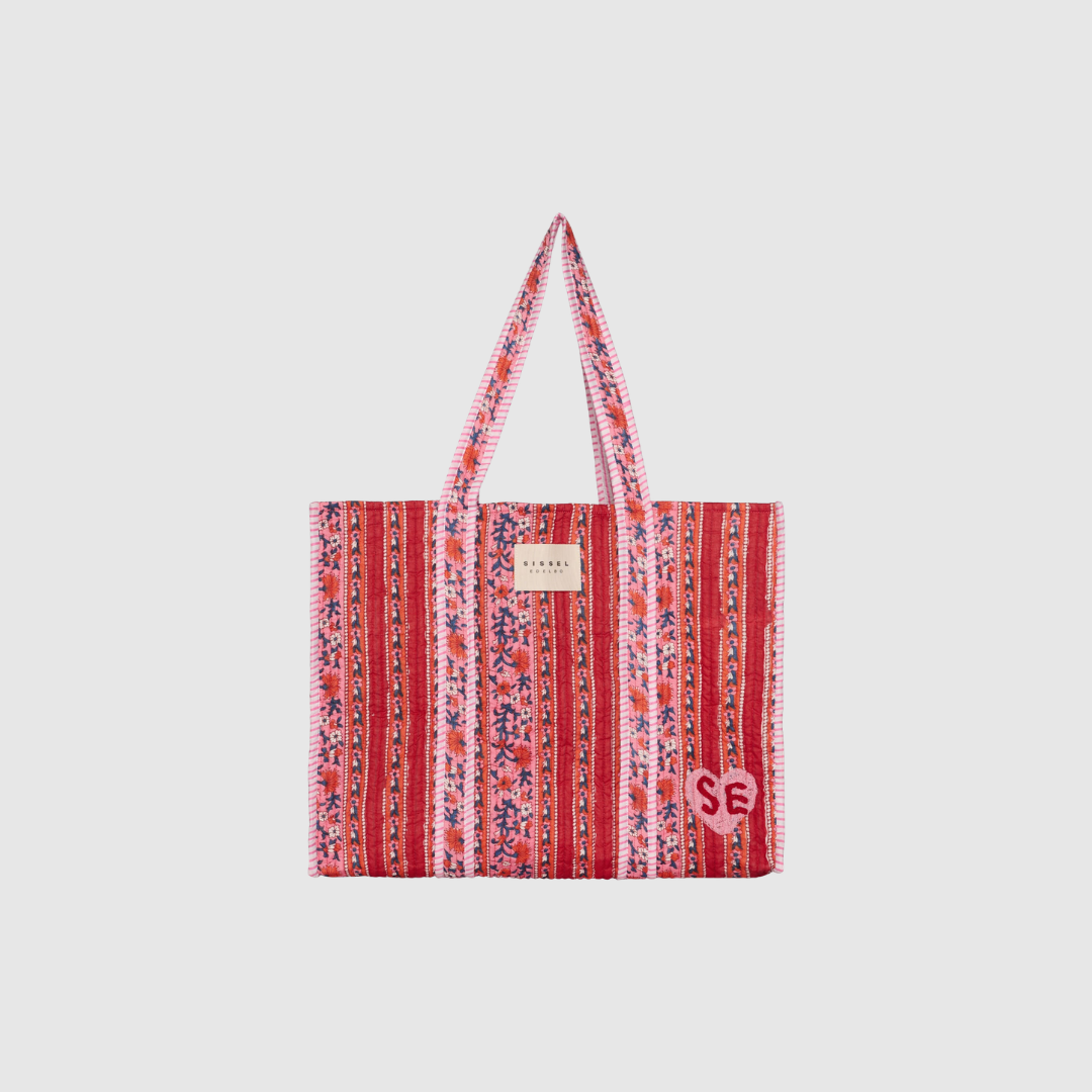 Pricilla Bag i Lavender Bloom er en quilt‑syet taske i 100 % økologisk bomuld. En rummelig og stilfuld hverdagstaske med håndlavet print, indvendig lomme og smukke detaljer. Find Pricilla Bag hos Merci Give.