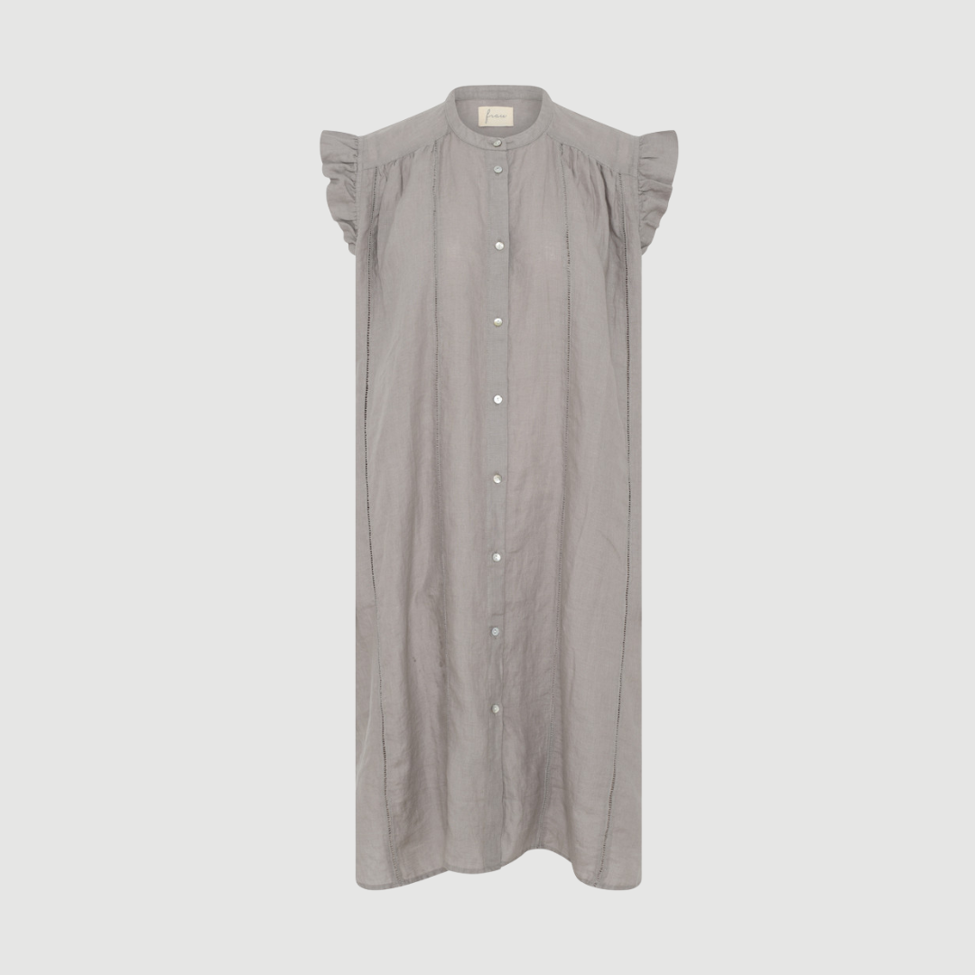 Napoli Pure Linen Deco Knee Dress i Dove er en feminin hørkjole med dekorativt bånd, flæsedetaljer og bindebælte. En let og elegant sommerkjole i 100 % hør.