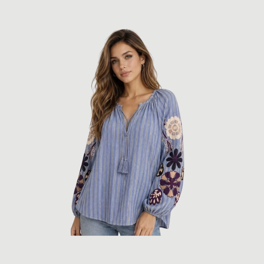 Isadora Shirt i Heather Blue er en feminin bomuldsbluse med broderede blomster, bindebånd og stribet design. En romantisk og boheme-inspireret bluse perfekt til hverdag og sommer.